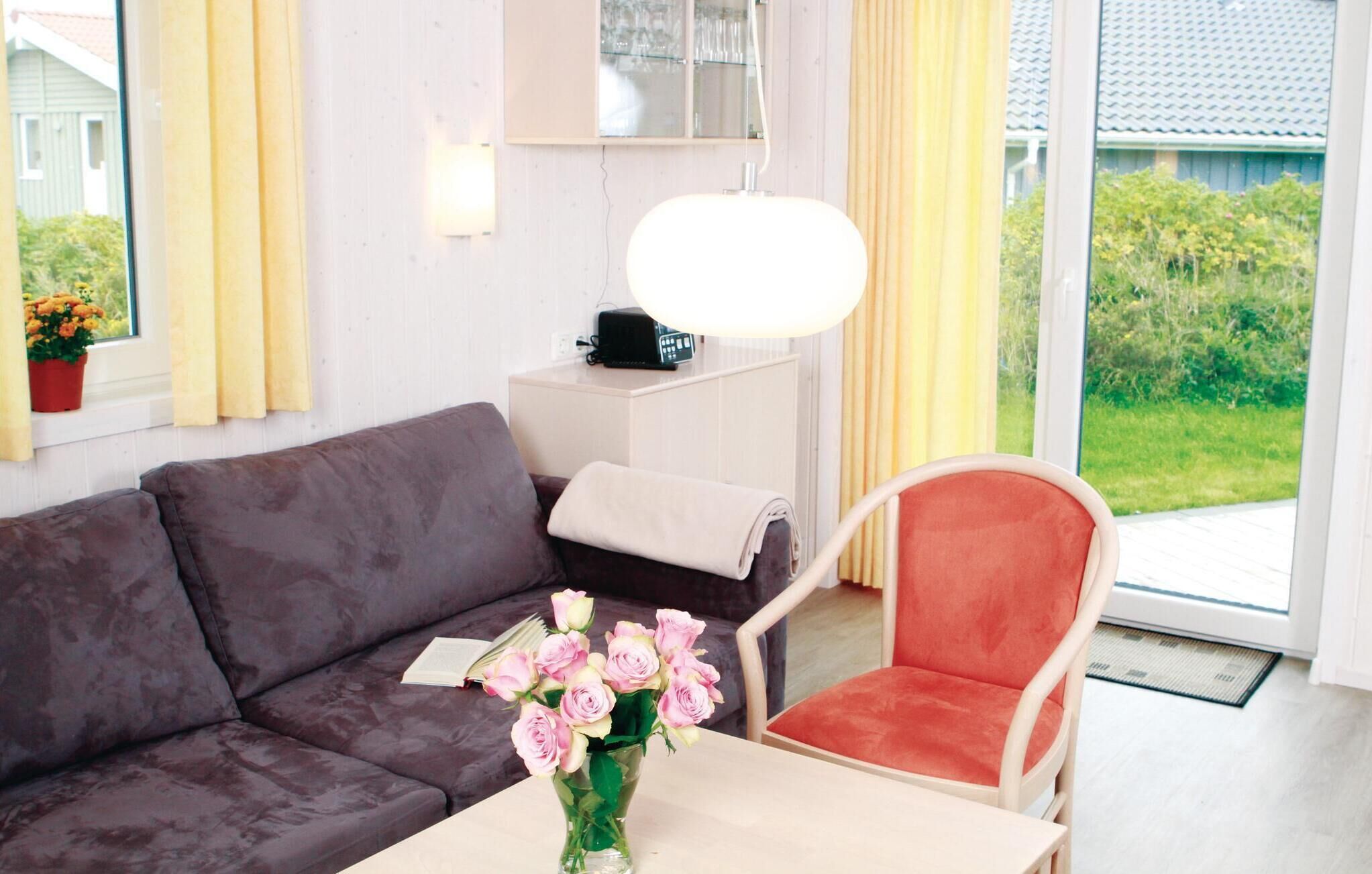 A modern living room with a dark brown sofa, a red chair, a white table, and a vase of pink flowers.