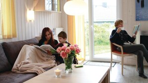 Un salon chaleureux avec un canapé, une table sur laquelle est posée une bougie et un vase rempli de fleurs.