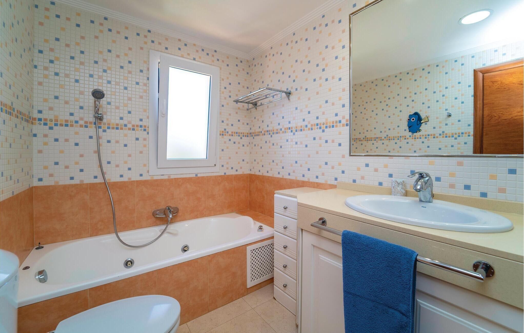 Un baño con bañera, lavamanos, inodoro y ventana.