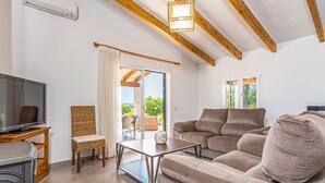 A living room with a sofa, a TV, a wicker chair, and a table. - Awesome home in Puerto de Alcudia (Puerto de Alcudia)