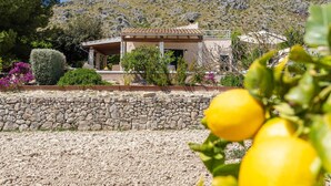 A stone wall, a building with a tiled roof, and a mountain in the background. - Awesome home in Puerto de Alcudia (Puerto de Alcudia)