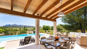 A covered outdoor dining area with a pool, dining table, chairs, and a view of the mountains. - Awesome home in Puerto de Alcudia (Puerto de Alcudia)