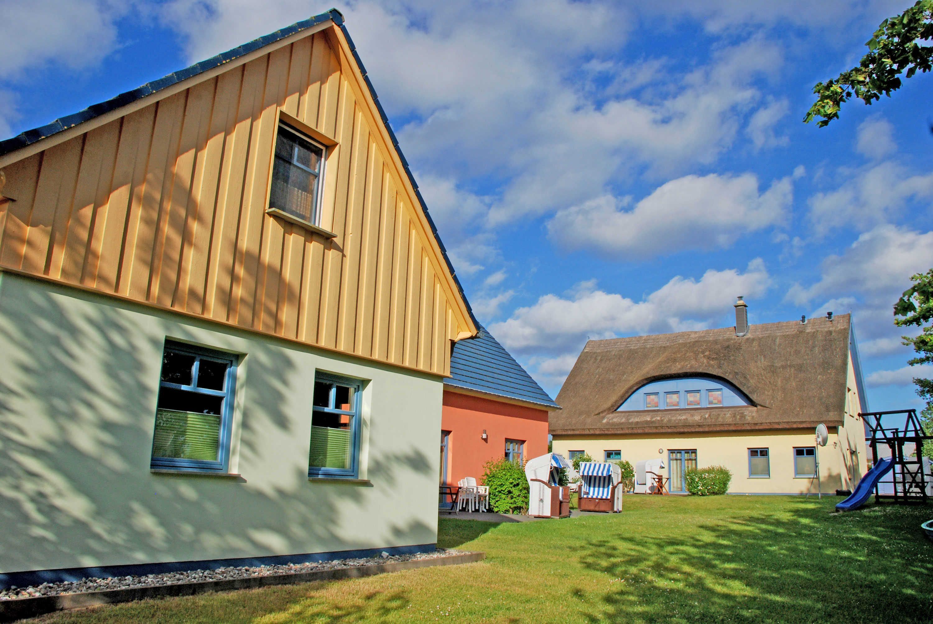 A traditional wooden house with a sloped roof, a small porch, and a play area with a slide.