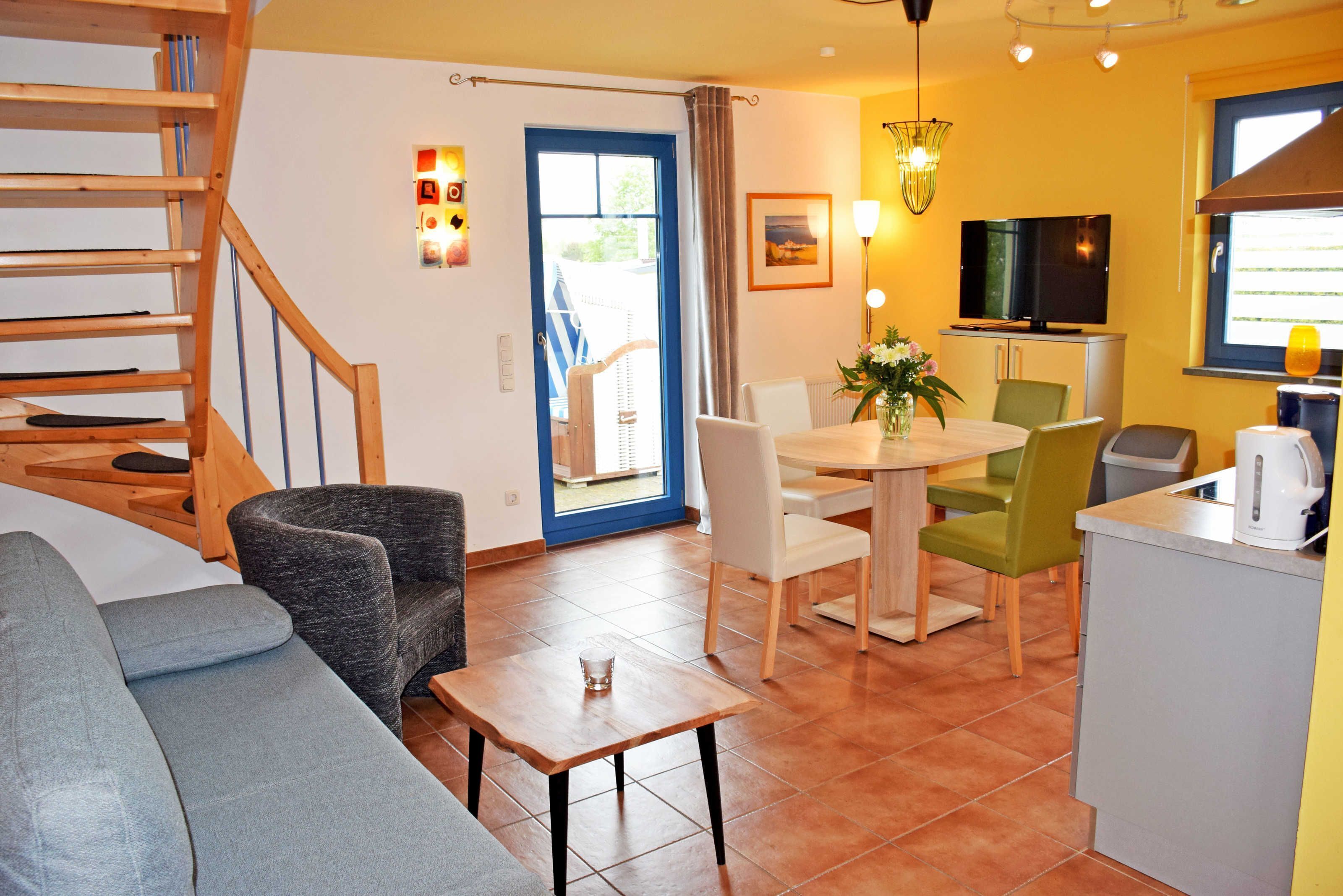 Una cocina moderna con comedor, una escalera y una sala de estar con sofá y sillones.