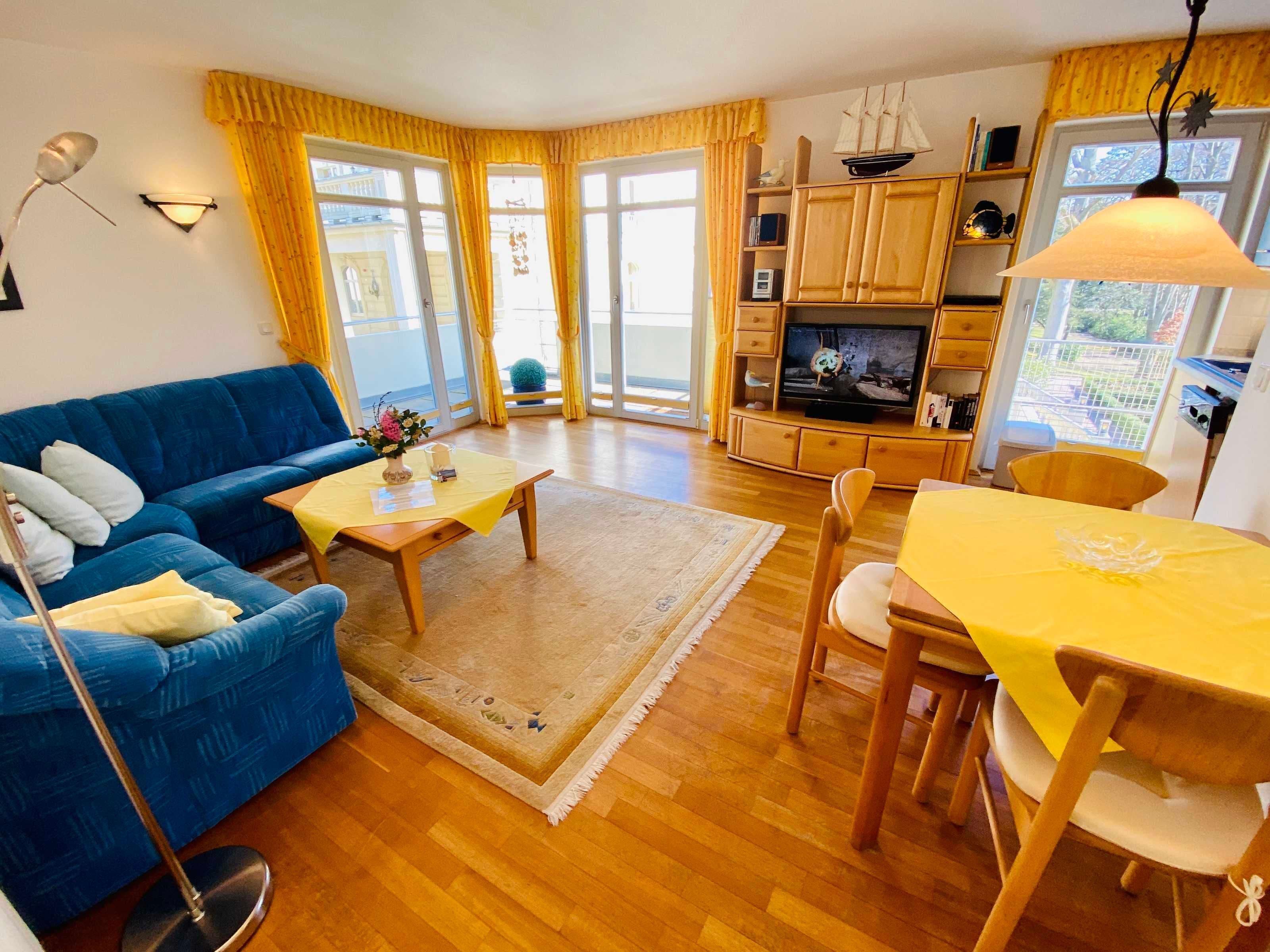 Ein Wohnzimmer mit einem blauen Sofa, einem gelben Tisch und einem Fernseher.