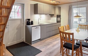 A compact kitchen with a dishwasher, coffee maker, and a dining area with a table and chairs.