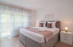 A bedroom with a bed, bedside tables, and a window with sheer curtains. - Awesome apartment in Dugi Rat with WiFi (Dugi Rat)