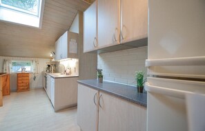A modern kitchen with wooden cabinets, a granite countertop, and a built-in oven. - Lovely home in Rømø with sauna (Rømø)