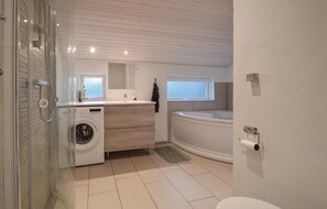 Ett modernt badrum med tvättmaskin, handfat och badkar.