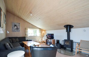 A cozy living room with a sofa, a glass coffee table, a TV, and a wood-burning stove. - Lovely home in Rømø with sauna (Rømø)