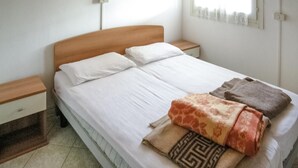 Una cama bien hecha con sábanas blancas, un cabecero de madera y dos mesitas de noche con cajones.