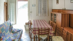 Una habitación acogedora con un sofá, una mesa de comedor con sillas, un armario de madera y vistas a través de una puerta.