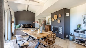 Un comedor moderno con una mesa grande, sillas de mimbre y una chimenea.