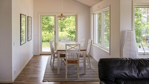 A dining area with a wooden table and chairs, large windows, and a view of greenery outside. - Stunning home in Bolmsö with sauna (Bolmsö)
