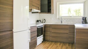 A modern kitchen with wooden cabinets, a white refrigerator, a stove, and a window above the sink. - Stunning home in Bolmsö with sauna (Bolmsö)