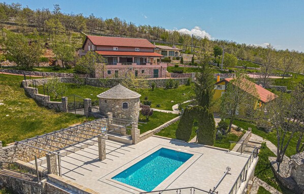 Relax by the spacious pool surrounded by lush gardens and a stone deck.