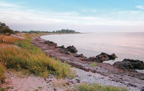 A coastal landscape with a rocky shoreline, a small boat, and a calm sea. - Beautiful home in Slite with kitchen (Slite)