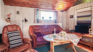 A cozy living room with a leather armchair, a purple sofa, a wooden coffee table, and a television. - Beautiful home in Slite with kitchen (Slite)