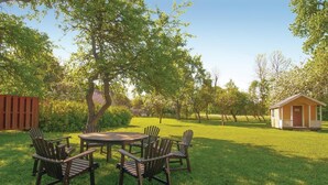 A backyard with a wooden table and chairs, a small shed, and a fenced area. - Beautiful home in Slite with kitchen (Slite)