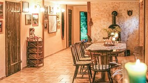 Zona pranzo con tavolo rotondo, sedie e lampadario. Alle pareti, quadri incorniciati e un mobiletto in legno con cesti.