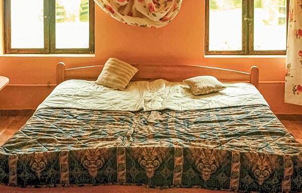 A bed with a patterned bedspread, two pillows, and a window with a floral curtain. - 4 bedroom cozy home in Sarnikierz (Sarnikierz)
