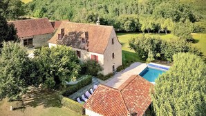 Una casa grande con piscina, rodeada de vegetación exuberante y árboles.