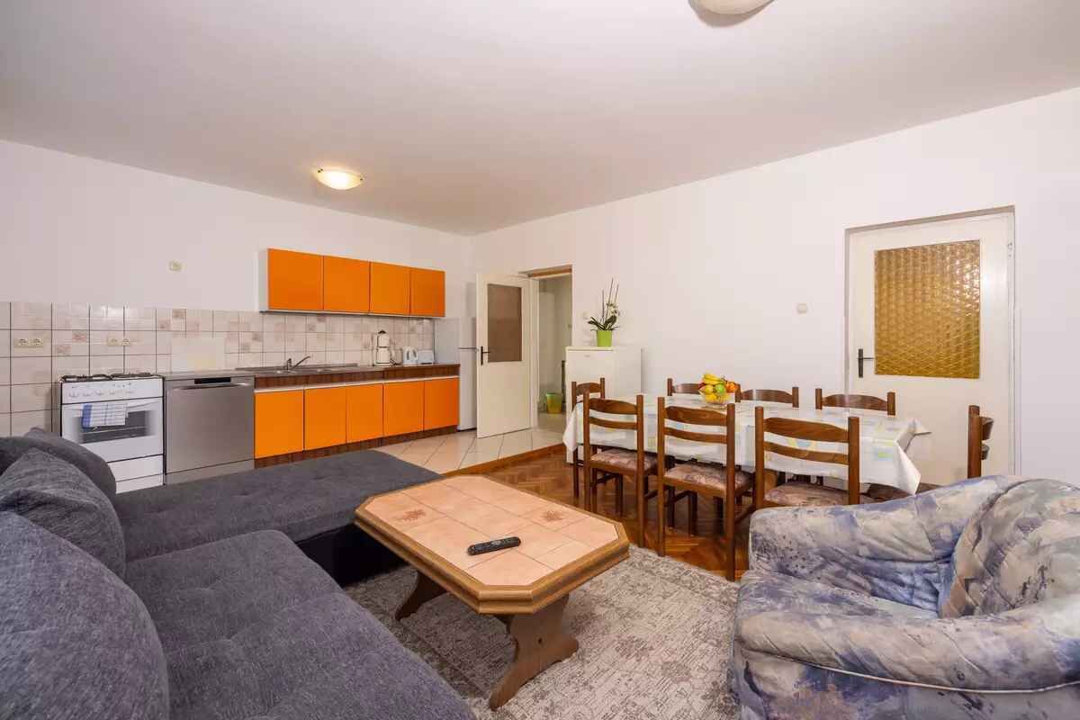 A compact living space with a kitchenette, a dining area, and a seating area with a sofa and a patterned armchair.
