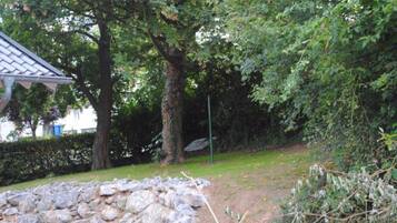 Un muro de piedra y una construcción de madera en un área boscosa.