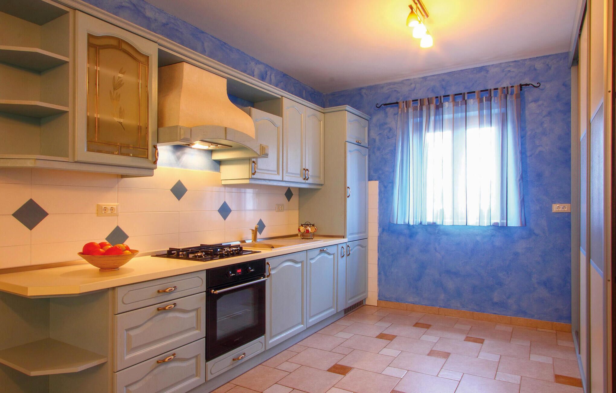 A kitchen with white cabinets, a gas stove, and a window with curtains.