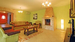 A living room with a fireplace, a sofa, a chair, and a coffee table. - Beautiful home in Vodnjan (Vodnjan)