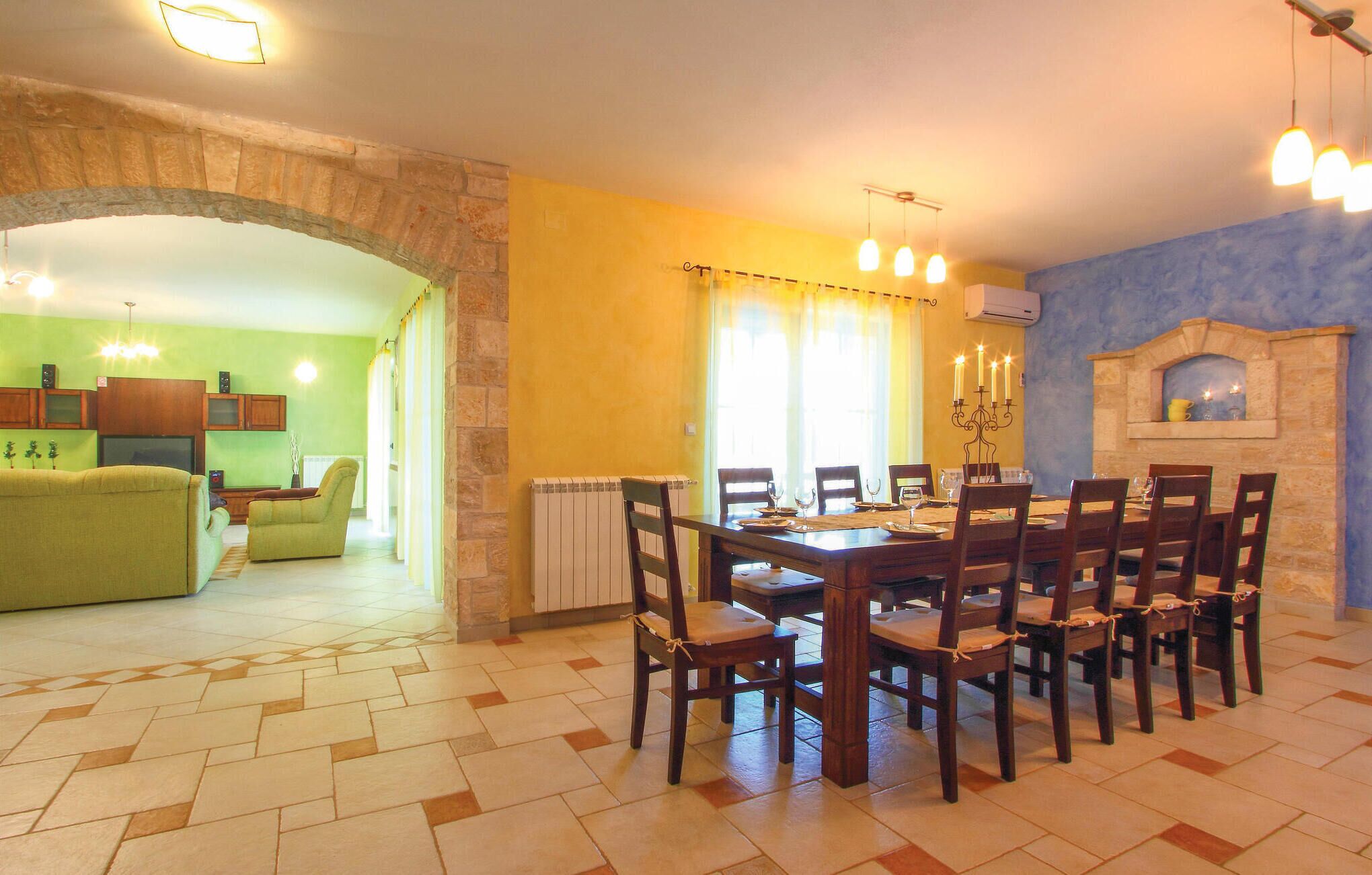 A dining area with a stone archway, a green sofa, and a fireplace.