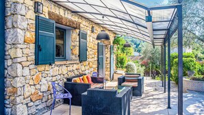A stone building with a covered patio area featuring wicker furniture and outdoor lighting. - 3 bedroom gorgeous home in Grasse (Grasse)