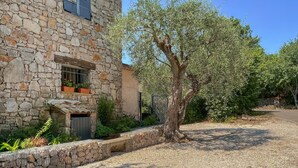 A stone building with a gravel driveway, a tree, and a metal gate. - 3 bedroom gorgeous home in Grasse (Grasse)