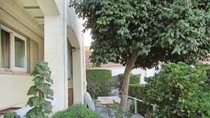 A covered outdoor area with a table and chairs, surrounded by various plants and a tree. - 1 bedroom nice apartment in Bastia (Bastia)
