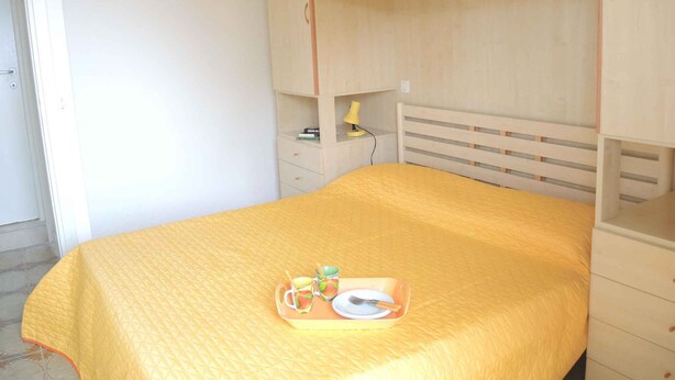 A bedroom with a bed, a bedside table, a lamp, and a tray with a plate, cup, and spoon.