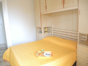 A bedroom with a bed, a bedside table, a lamp, and a tray with a plate, cup, and spoon.
