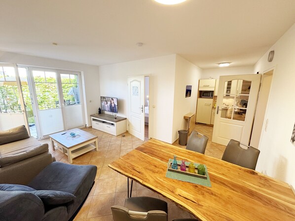 A compact living space with a dining area, kitchenette, and a TV in the living room.
