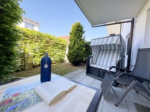 An outdoor patio with a table, a book, a blue water bottle, and a striped outdoor seating area.