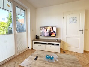 A living room with a TV on a wooden stand, a remote control, and decorative glass balls on a coffee table.