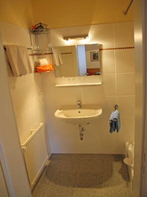 Un baño pequeño con lavamanos, espejo, toallero y retrete.