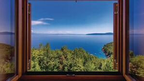 A view through a window of a large body of water, likely a sea or lake, with a clear sky and distant landforms. - Awesome apartment in Medveja with WiFi (Medveja)