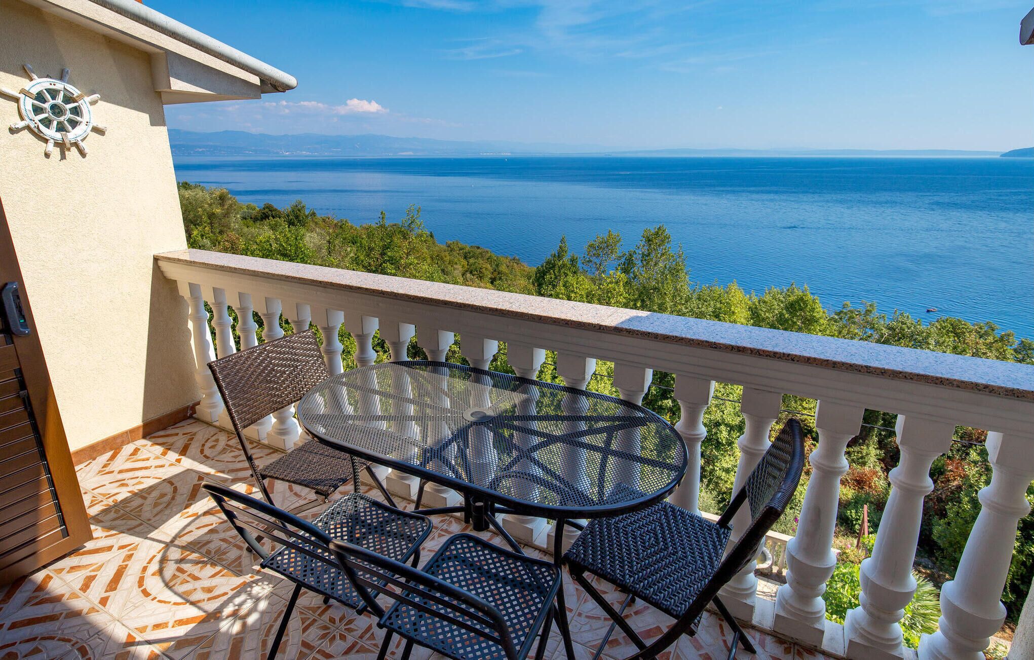 Ein Balkon mit Tisch und Stühlen mit Blick aufs Meer.