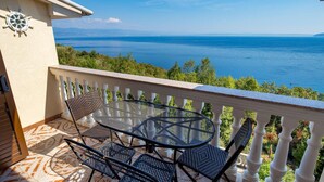 A balcony with a table and chairs, overlooking a sea view. - Awesome apartment in Medveja with WiFi (Medveja)