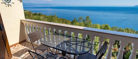 Ein Balkon mit Tisch und Stühlen mit Blick aufs Meer.