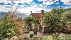 A coastal house with a stone staircase leading to a wooden door, surrounded by lush greenery and a view of the sea. - Awesome apartment in Medveja with WiFi (Medveja)