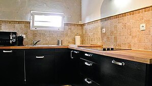 Cucina con mobili scuri, un piano di lavoro in legno e una finestra sopra il lavello.