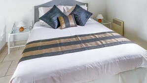 Un letto rifatto con coperta a righe, due comodini con lampade e un termosifone sulla parete.