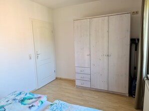 A room with a wooden wardrobe, a white door, and a bed with floral bedding. - Vacation apartment Schick - Holiday apartment Schick (Trassenheide)