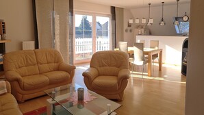 Ein geräumiges Wohnzimmer mit zwei Ledersofas, einem Glastisch und einem Essbereich mit Holztisch und Stühlen.