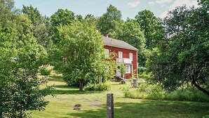 A red house surrounded by lush greenery and trees. - Stunning home in Hovmantorp with WiFi (Hovmantorp)